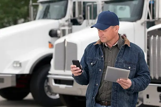 Driver reviewing shipment details beside trucks