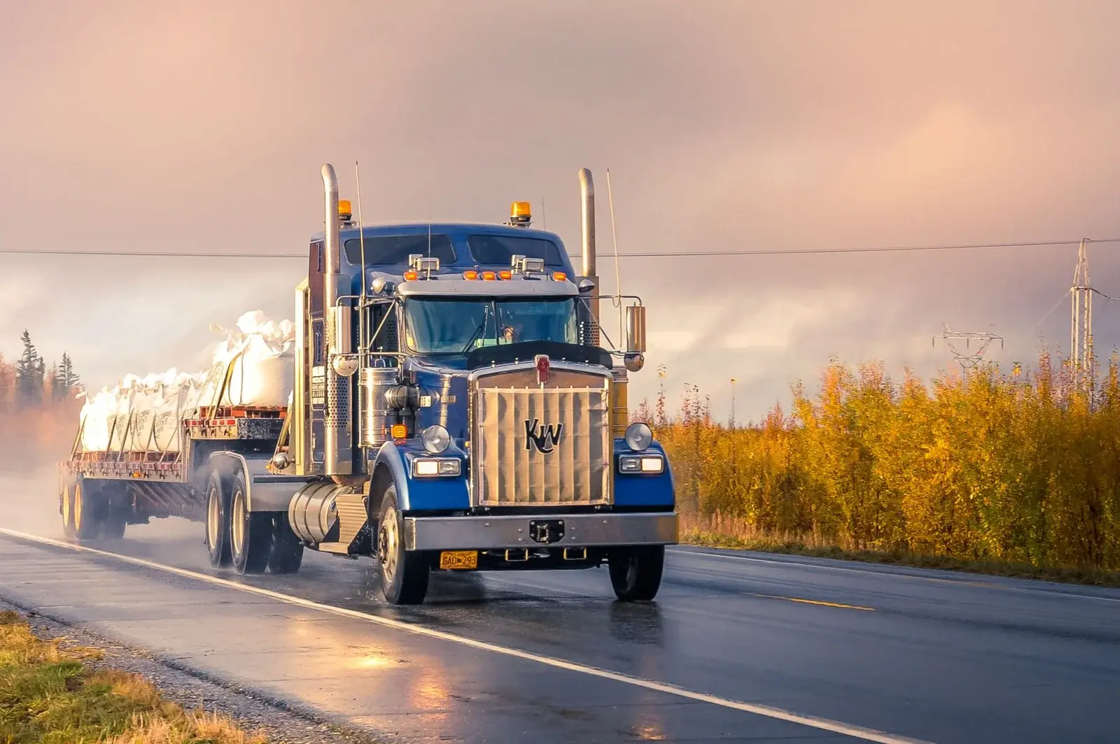 Semi tractor hauling a loaded flatbed trailer