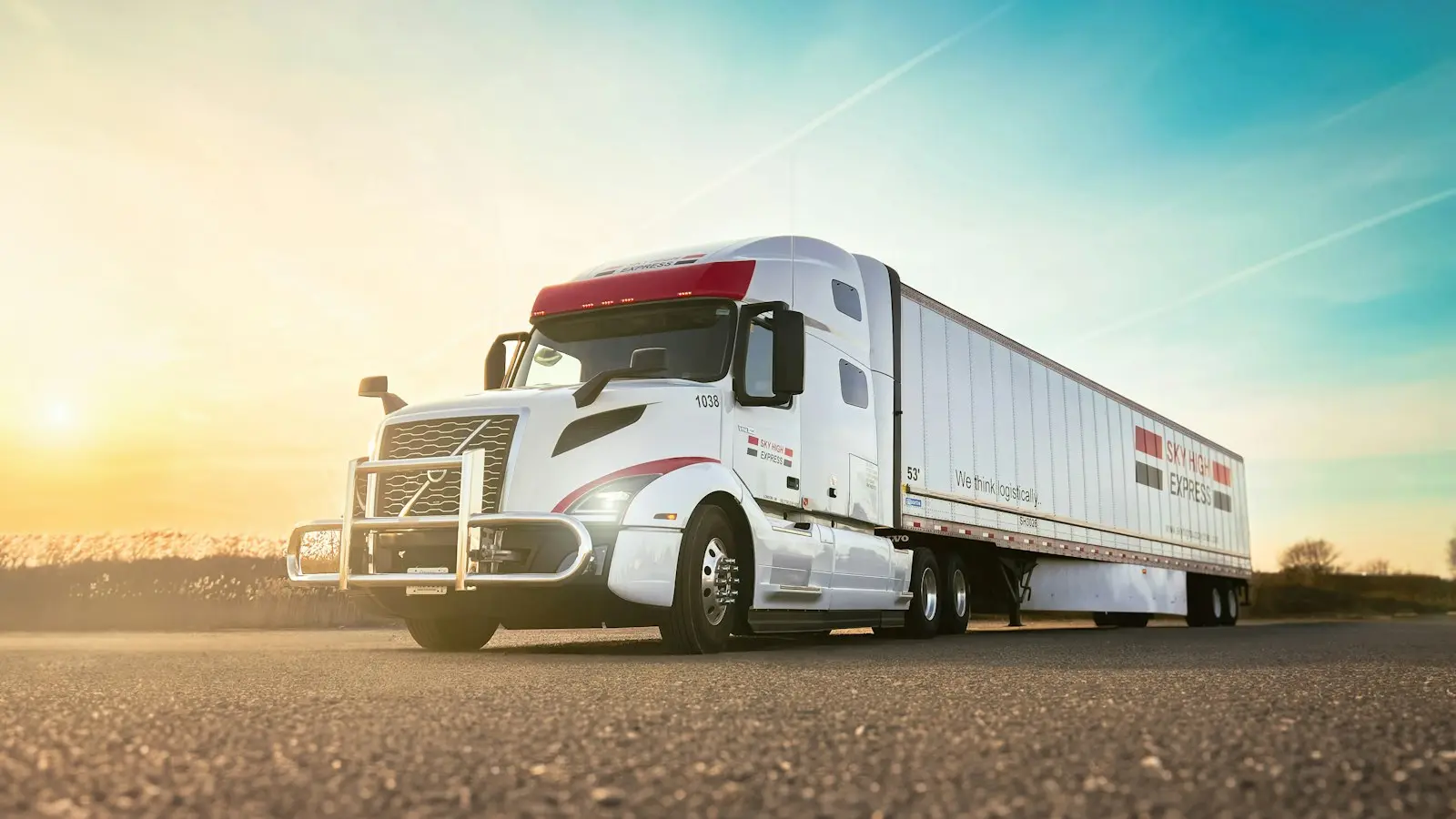 White Class 8 tractor with trailer at sunset