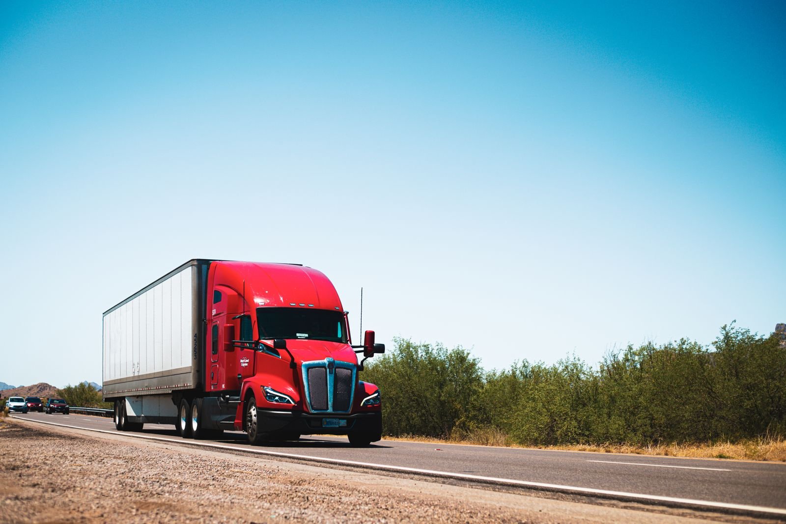 Red Class 8 tractor pulling a trailer on a US highway